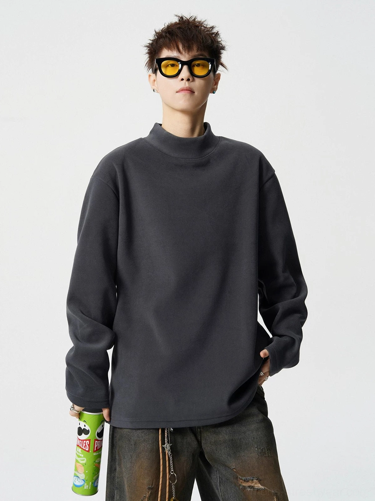 Dark grey boxy mock neck fleece streetwear top styled with baggy denim and yellow tinted sunglasses