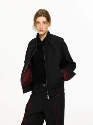 Model wearing an unzipped black floral-lined bomber jacket and wide-leg trousers with red floral details