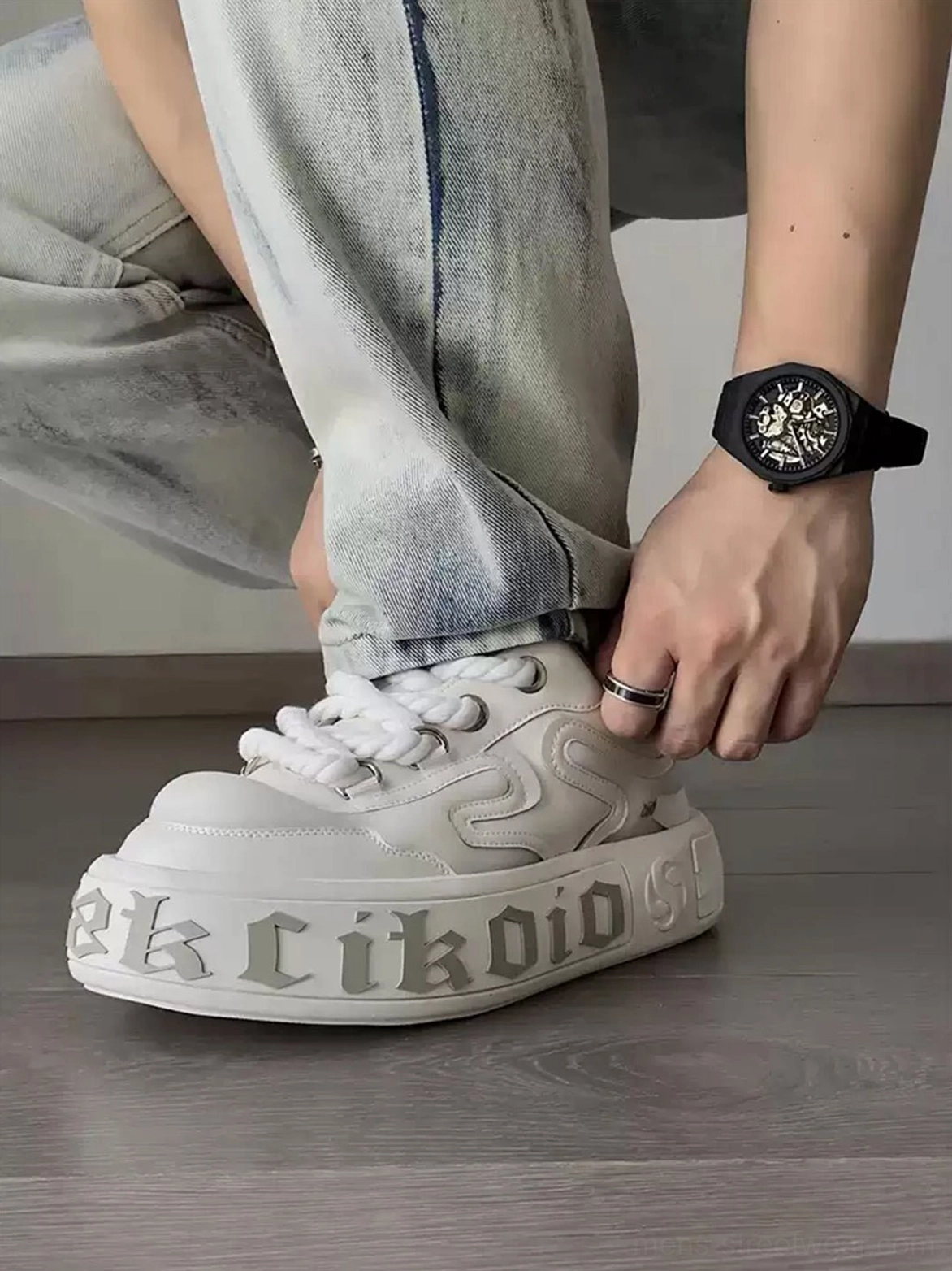 Model wearing chunky white platform skate sneakers with light wash denim jeans in a casual streetwear outfit