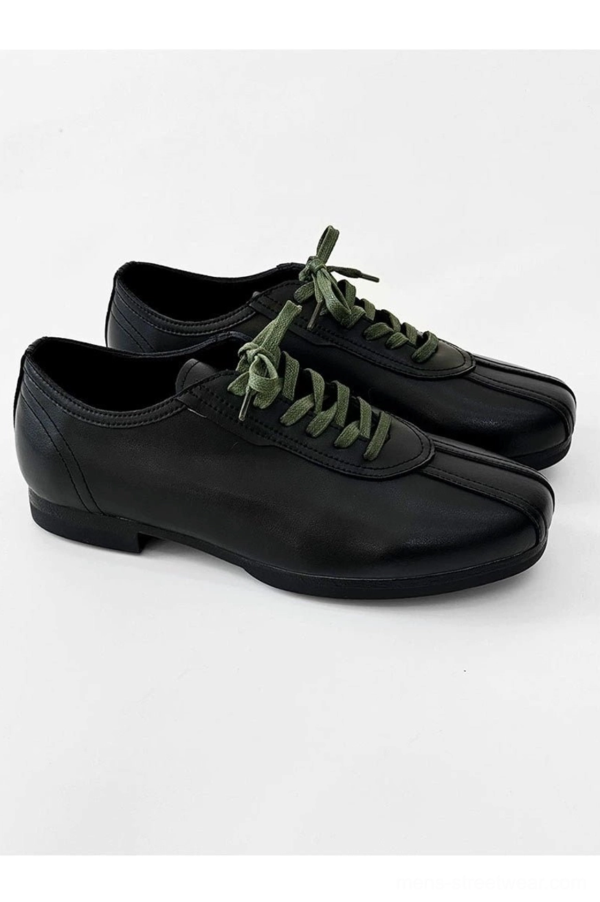 Modern black split-toe derby shoes with bright green laces, structured lace-up front, and understated avant-garde styling