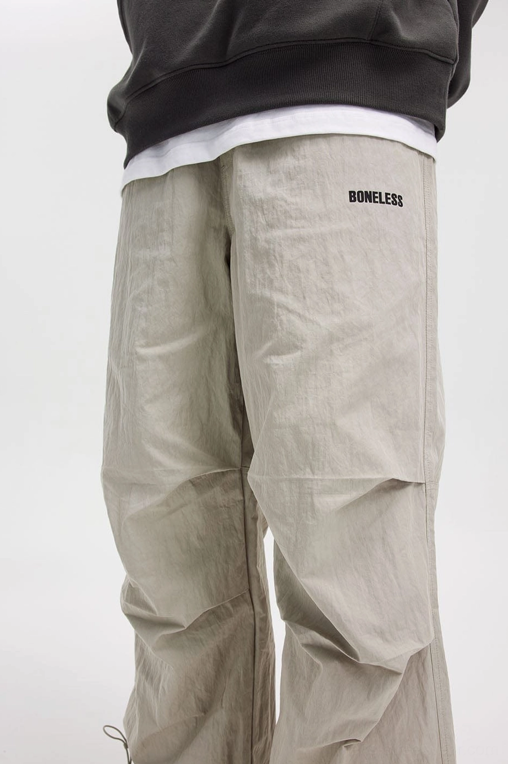 Modern Korean streetwear track pants with a wide-leg silhouette, drawstring hems, and textured crinkle finish
