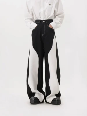 Front view of monochrome black and white wave panel wide-leg streetwear trousers styled with a striped shirt and chunky black leather shoes