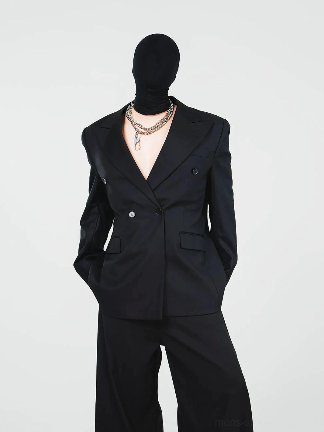 Avant-garde black tailored blazer and long wide-leg trousers side view with layered silver chain styling