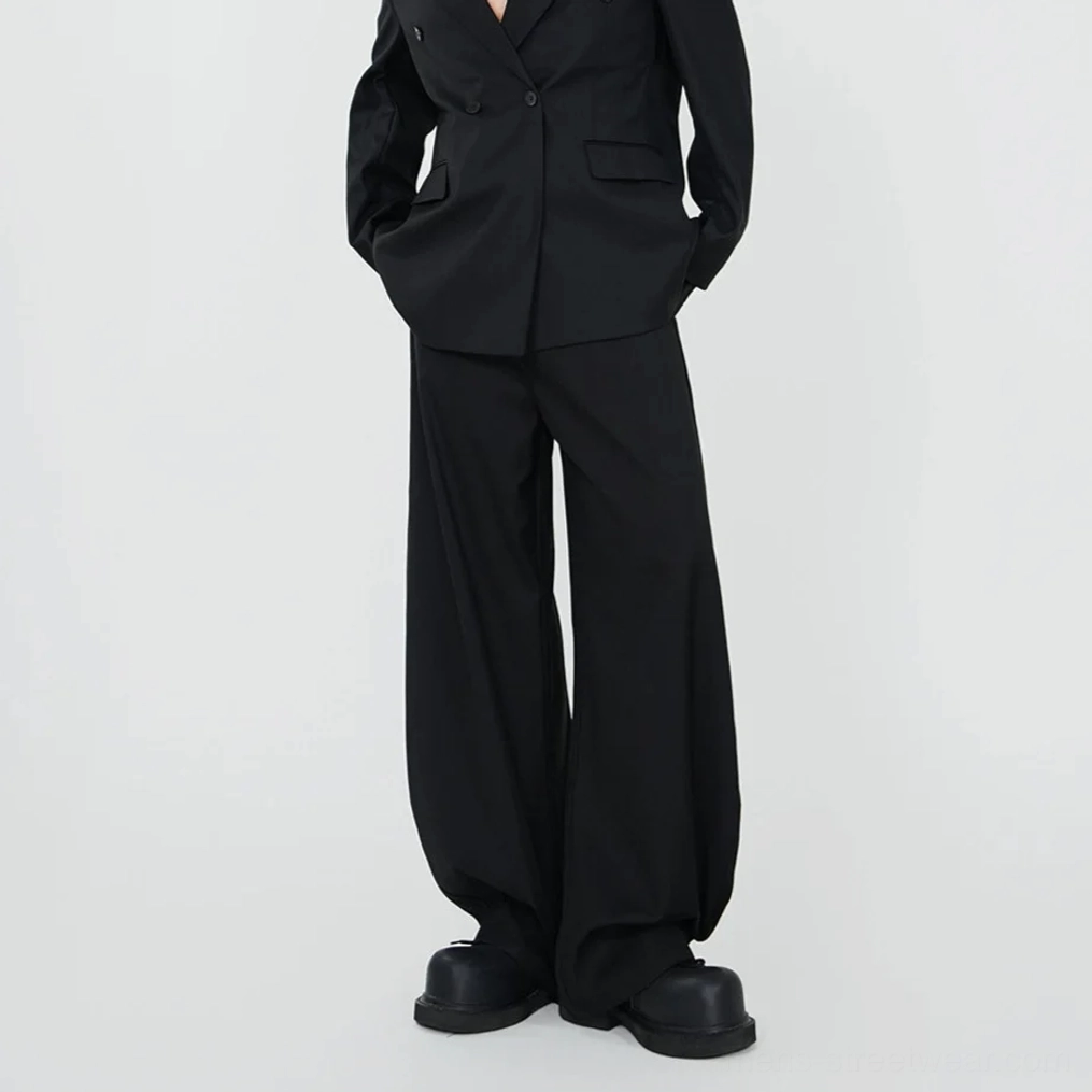 Black draped wide-leg trousers and double-breasted blazer shown from back three-quarter view with platform boots