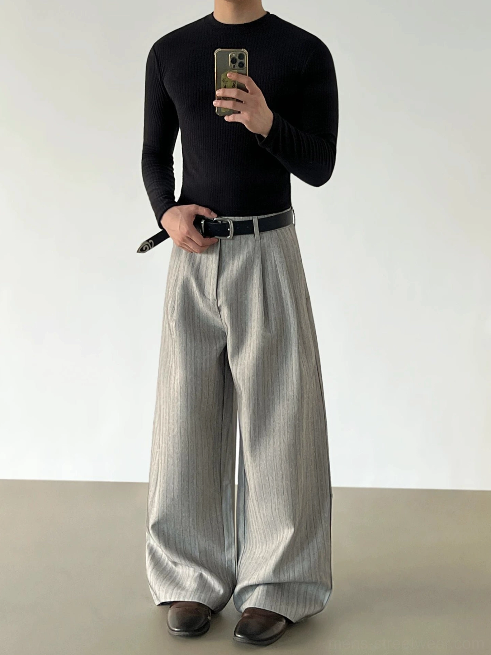 Gray pinstripe pleated wide-leg trousers in a front three-quarter mirror view styled with a black fitted knit top and brown leather shoes