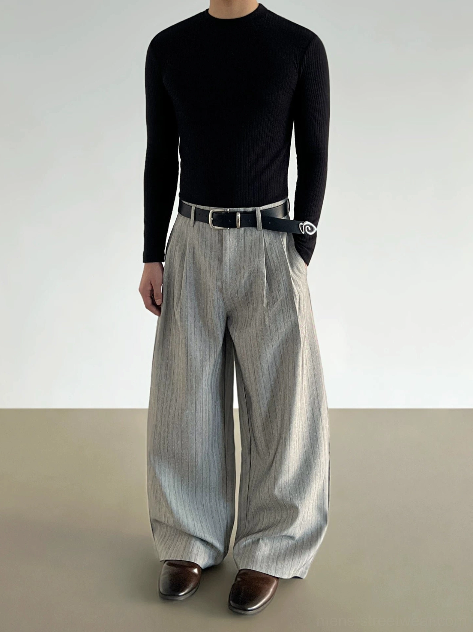 Side three-quarter view of gray striped oversized wide-leg trousers with front pleats belt loops and flowing streetwear fit