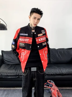Front view of a red and black motorcycle racing varsity jacket with racing patches, number graphic, black T-shirt, dark jeans, and sneakers