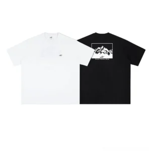 Black and white mountain frame graphic tees displayed side by side in a flat lay with minimalist chest detail and bold snow mountain back artwork