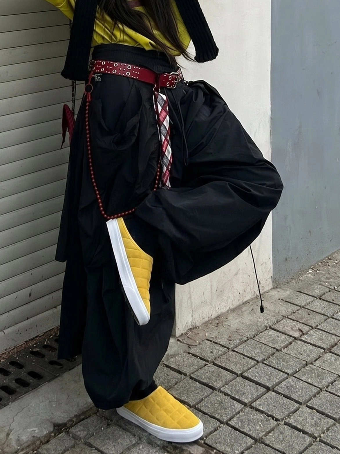Mustard yellow quilted backless sneaker mules worn with dark wide-leg pants in an urban streetwear setting