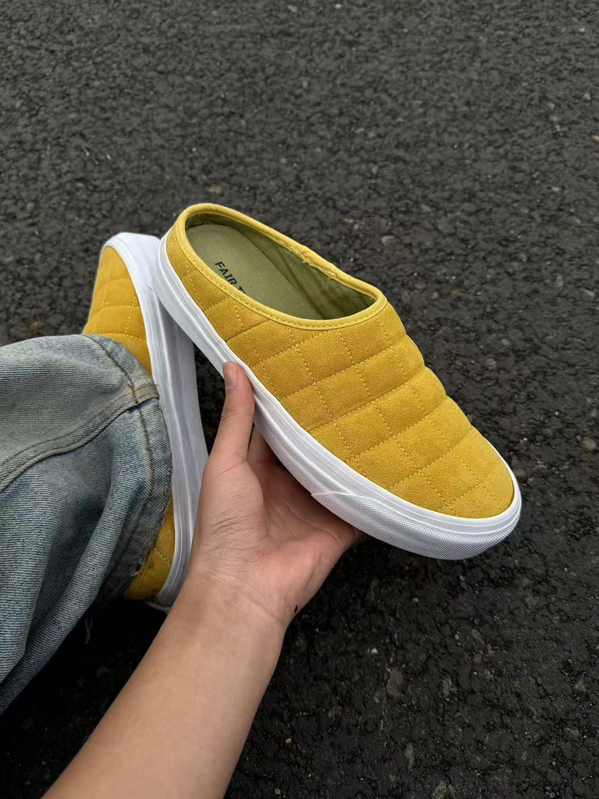 Close side view of mustard yellow quilted streetwear sneaker mule paired with blue denim jeans