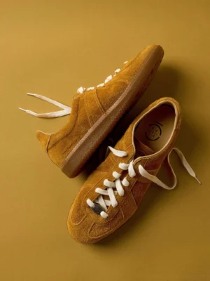 Mustard yellow suede heritage sneakers with classic retro trainer silhouette, cream laces, and gum sole