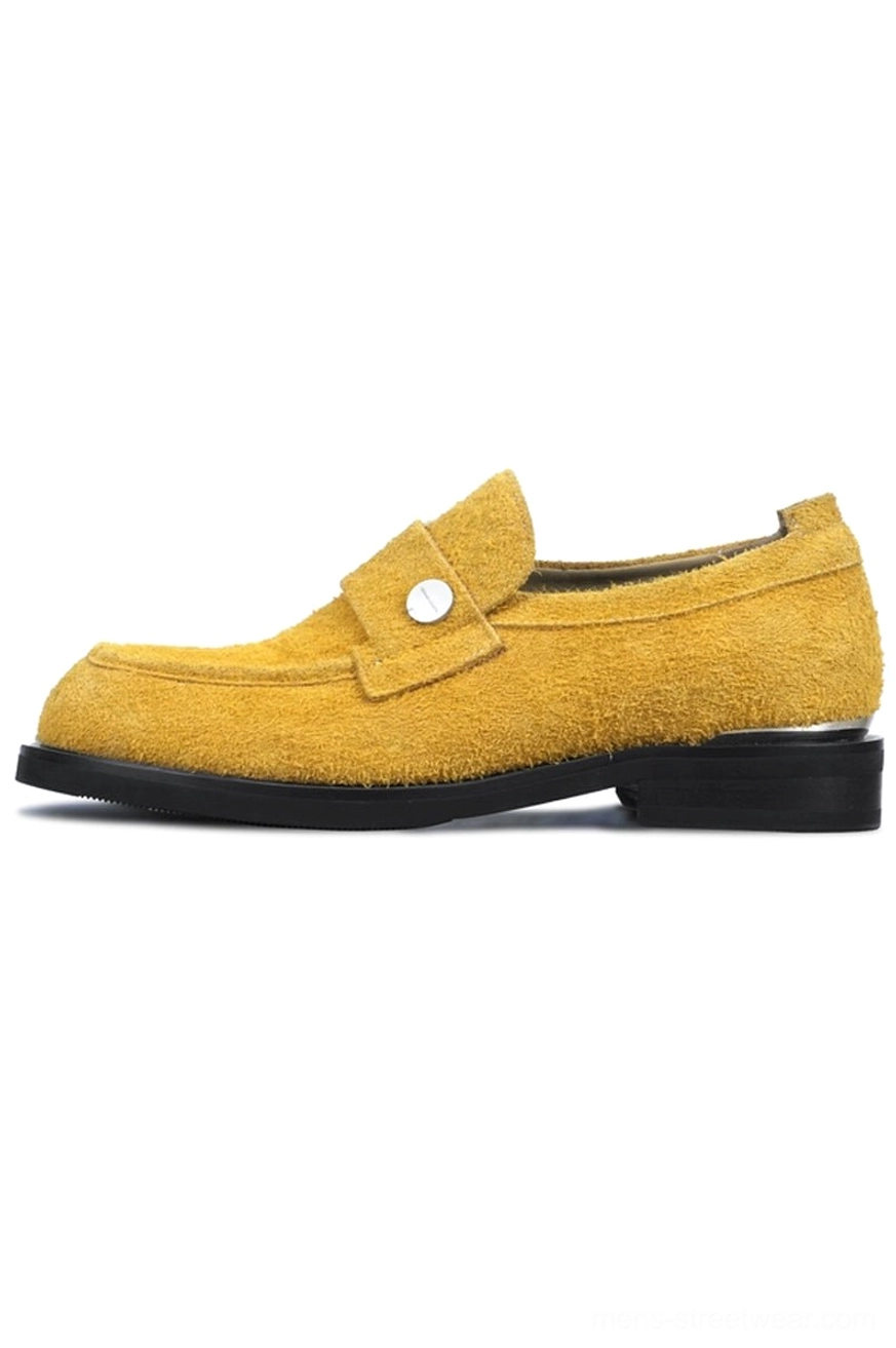 Mustard yellow suede penny loafers with fuzzy textured upper silver strap detail and low metallic heel on white background