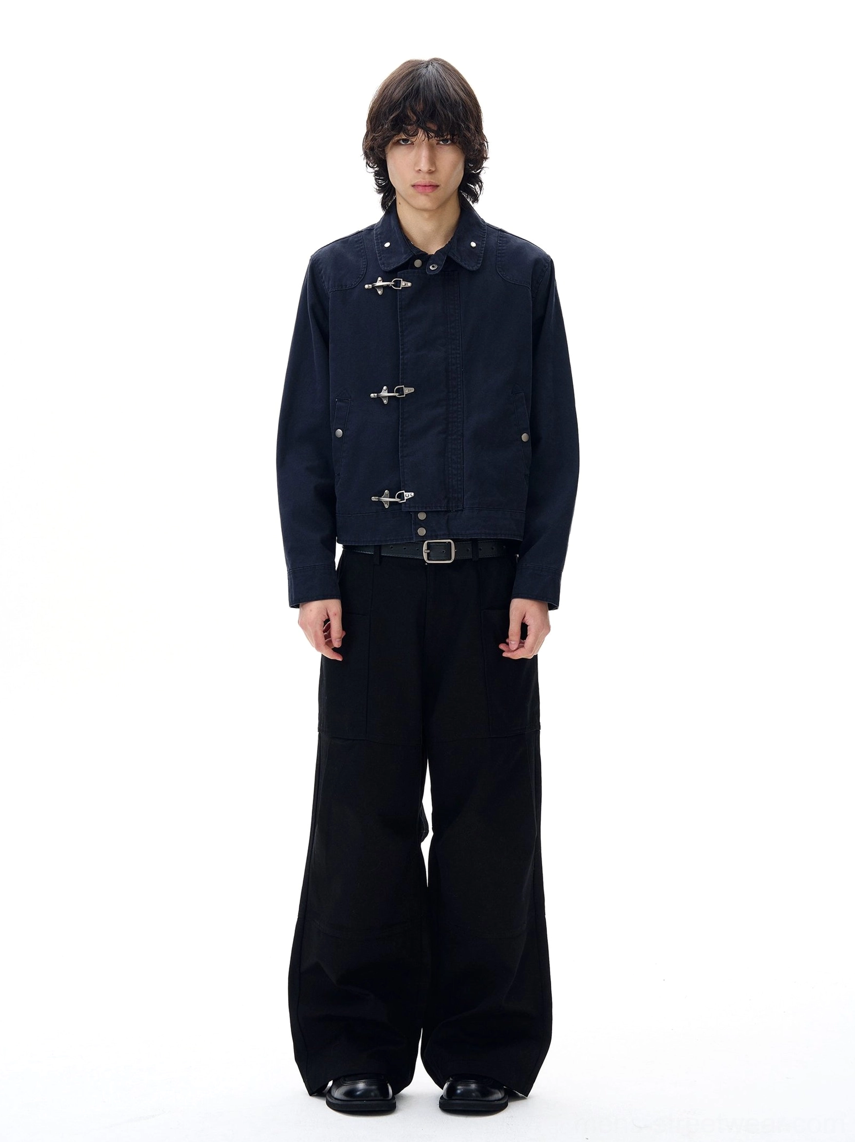 Navy blue metal toggle cropped utility jacket front view styled with black wide-leg trousers in a minimalist studio