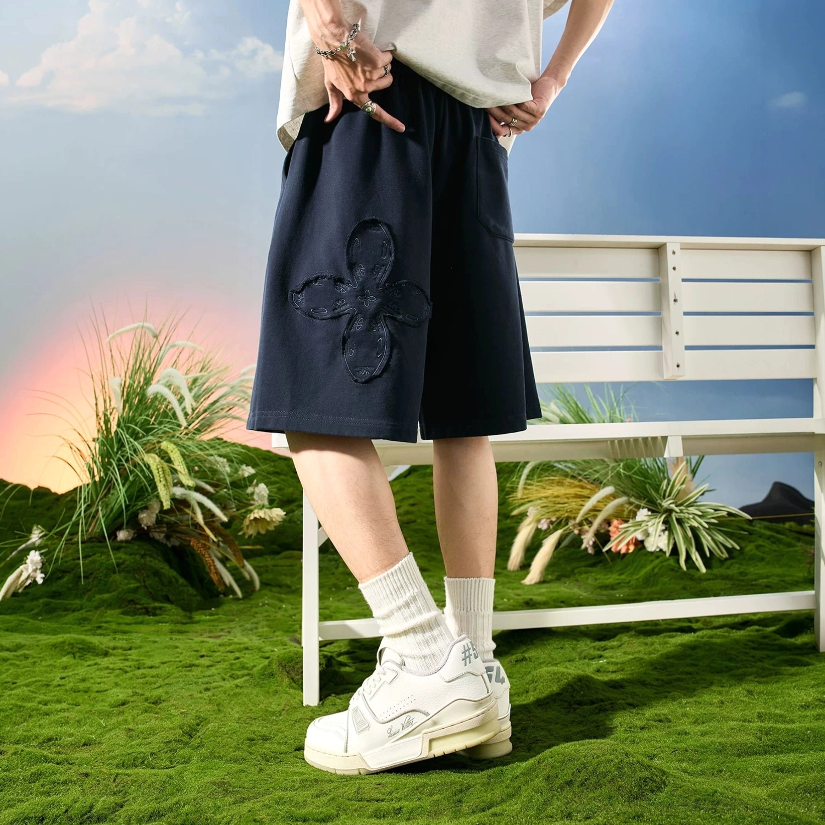 Navy blue relaxed floral appliqué sweat shorts with side pockets shown from a low three-quarter side view