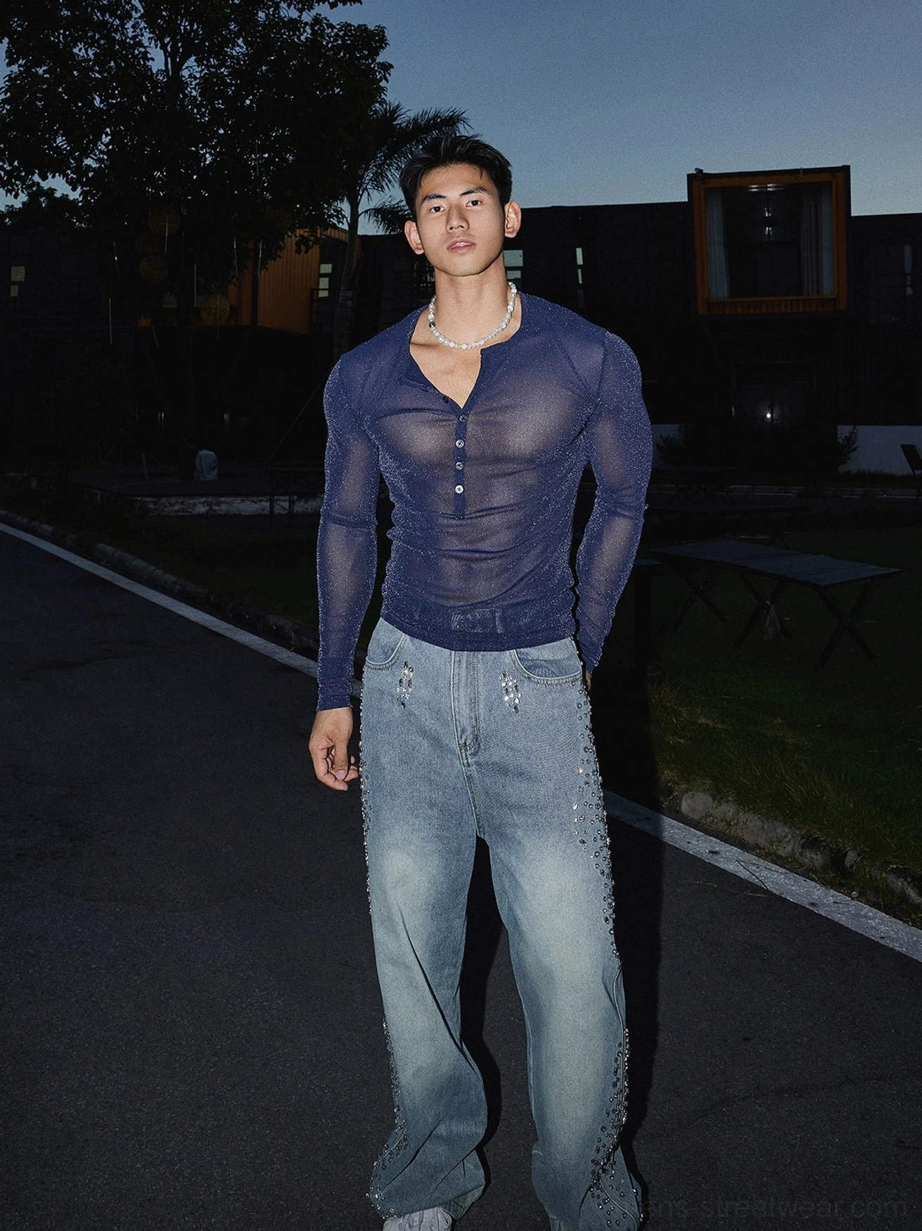 Full-length male streetwear outfit featuring a navy blue sheer sparkly Henley top with distressed jeans and open neckline