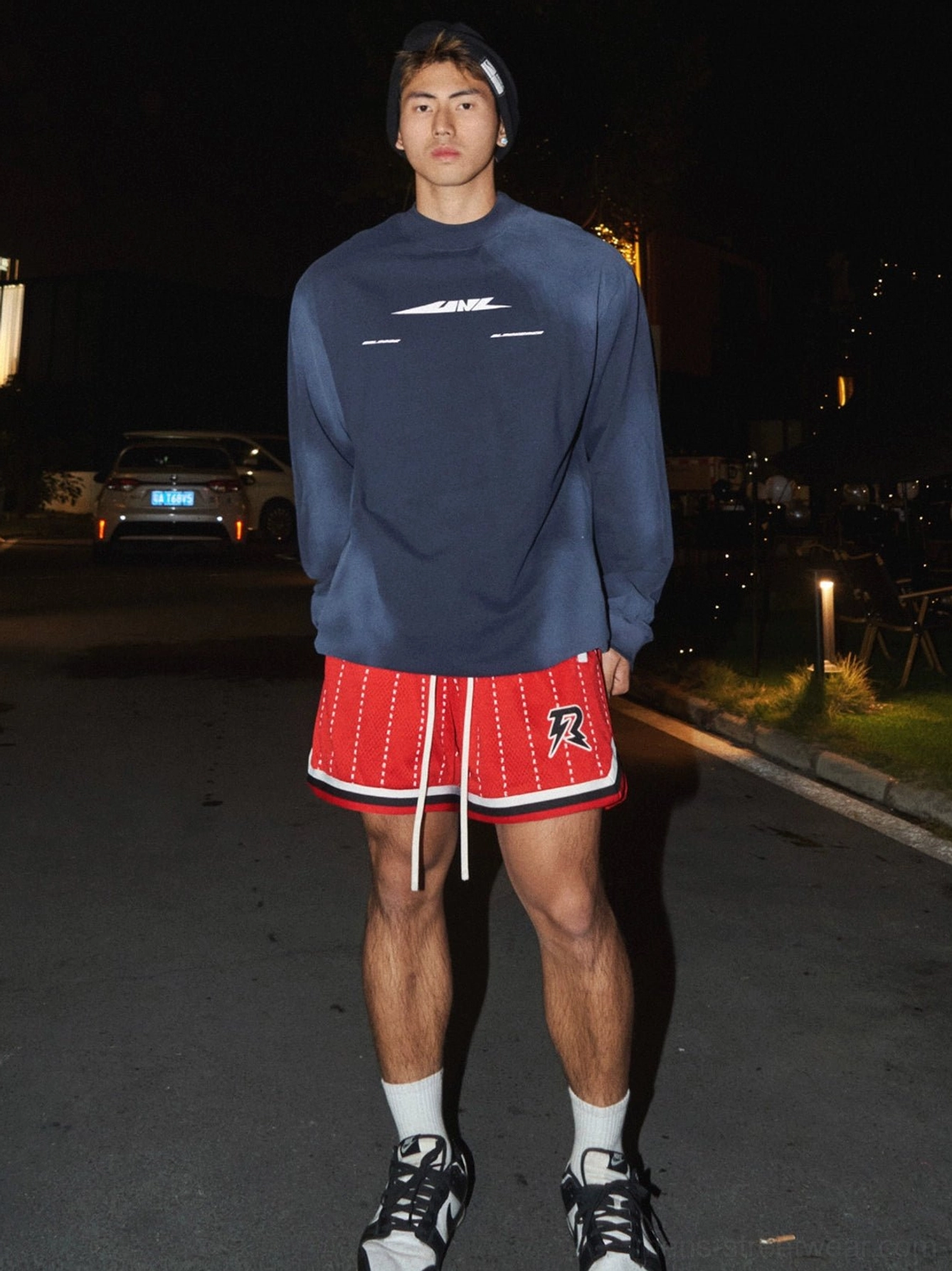 Navy blue washed tech logo oversized streetwear sweatshirt worn by male model on a nighttime city street with shorts and sneakers