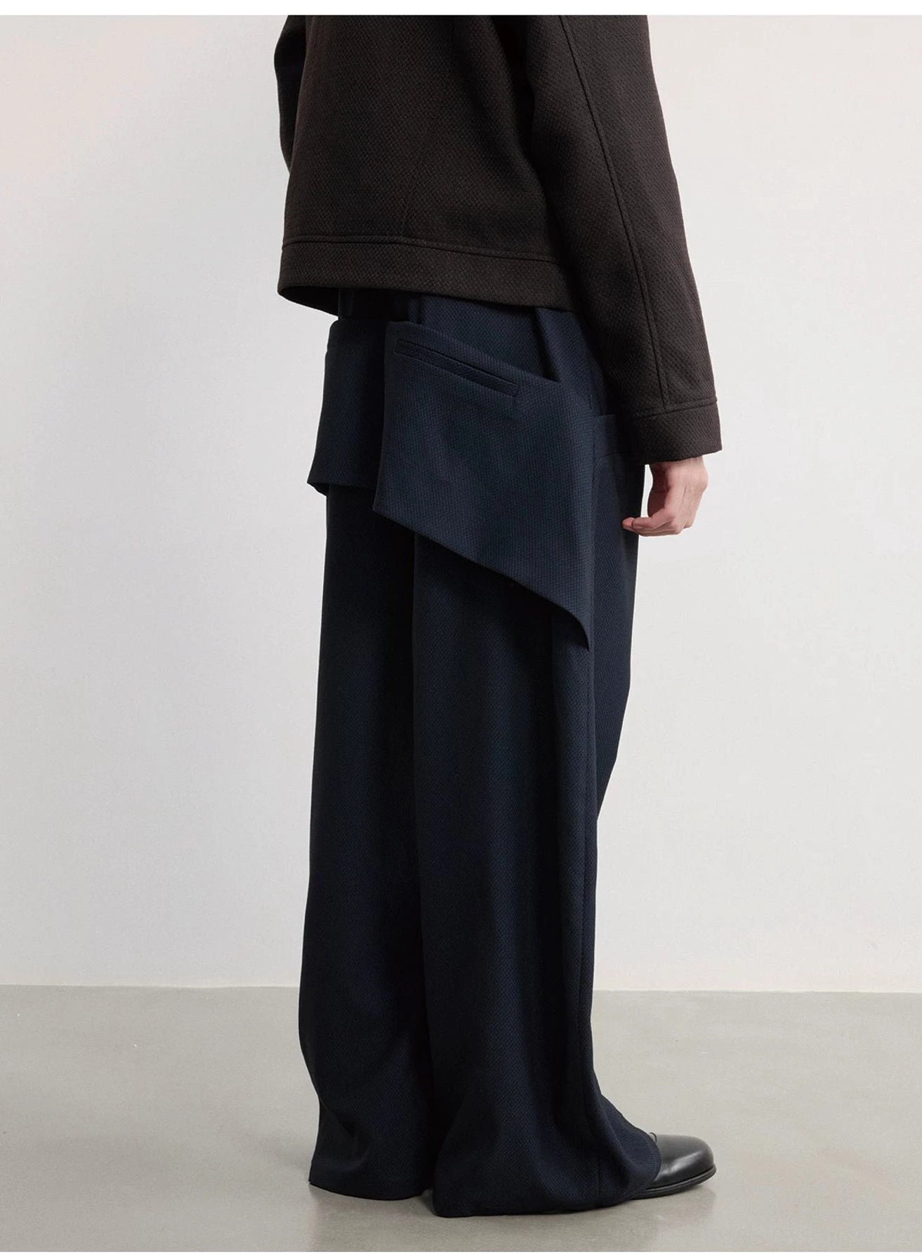 Side view of navy oversized wide-leg trousers with detachable zipper pouch and flowing full-length silhouette