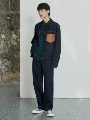 Navy double-pleated dress pants styled with a denim jacket and canvas sneakers in a casual streetwear outfit