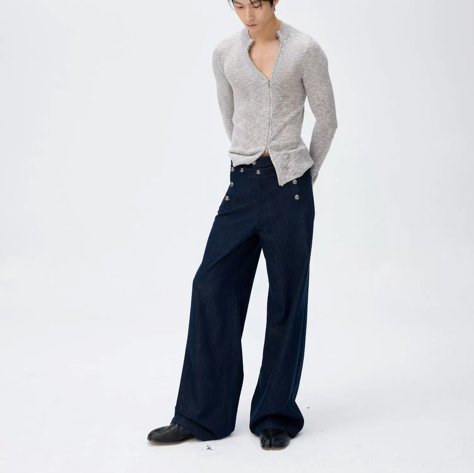 Side rear view of dark navy high-waisted wide-leg sailor trousers with double metal button waistband styled with a grey half-zip knit top