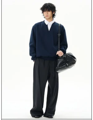 Three-quarter view of navy oversized streetwear sweatshirt styled with wide-leg black trousers and a black leather duffel bag