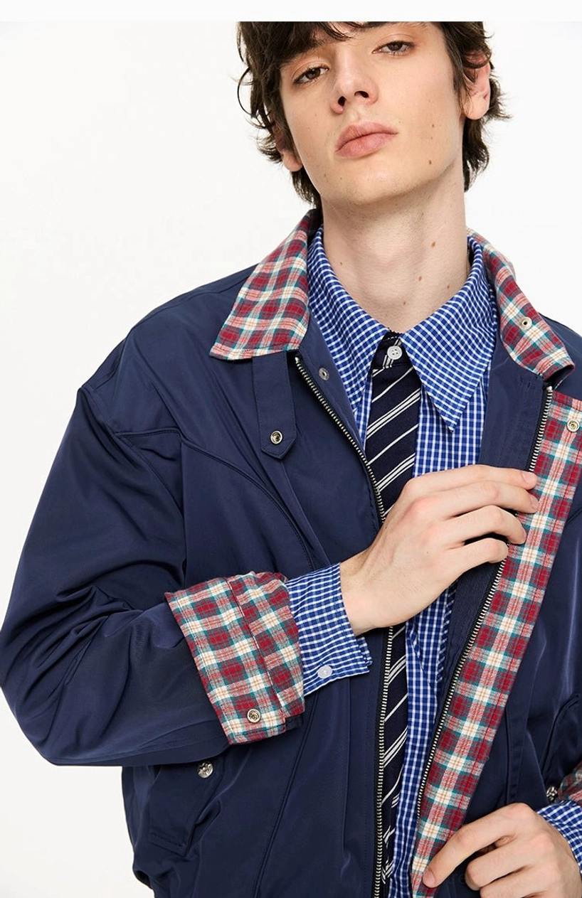 Close-up of navy plaid-lined cropped Harrington jacket showing metal snap hardware stand collar check lining and seam details