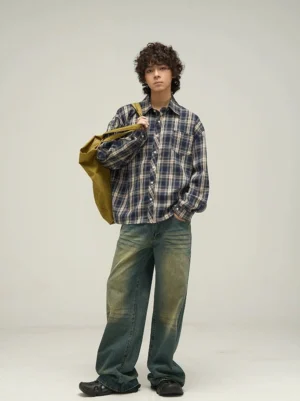 Three-quarter front view of navy plaid oversized long sleeve shirt styled with wide-leg jeans and canvas tote bag