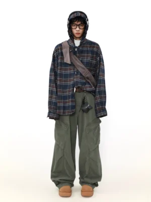Full body view of an oversized navy and red checkered hooded button-up shirt styled with wide-leg olive cargo pants and tan boots