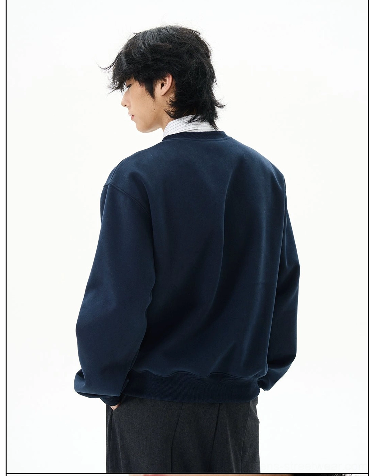 Side back view of a navy relaxed-fit sweatshirt highlighting the oversized body, ribbed cuffs, and ribbed waistband