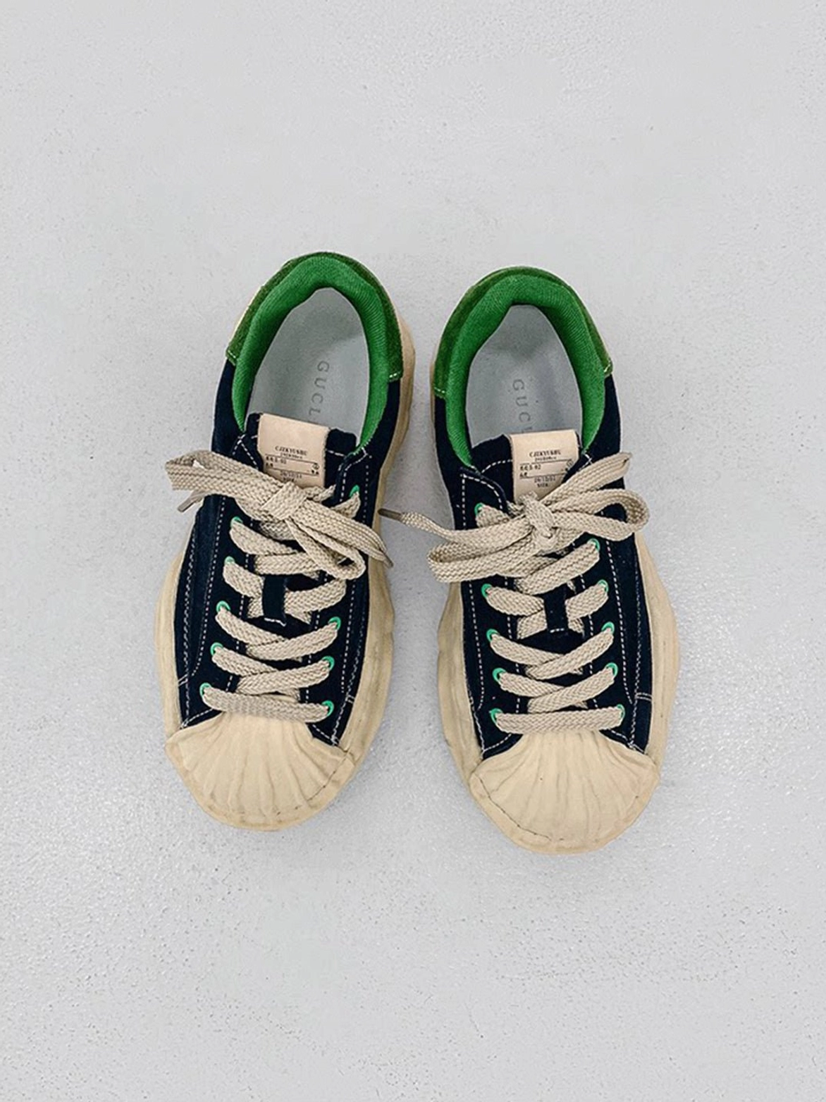 Navy blue shell-toe platform sneakers with green lining, round laces, cream chunky sole, and retro casual silhouette