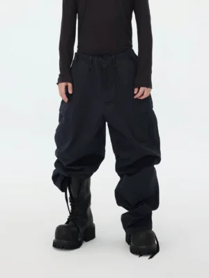 Front full-body view of oversized deep navy stacked cargo pants with wide-leg fit, large utility pockets, adjustable ankle drawcords, and chunky black work boots