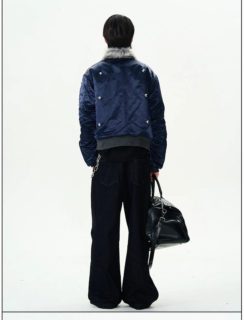 Back view of a navy studded bomber jacket with grey faux fur collar and ribbed hem worn with black wide-leg pants