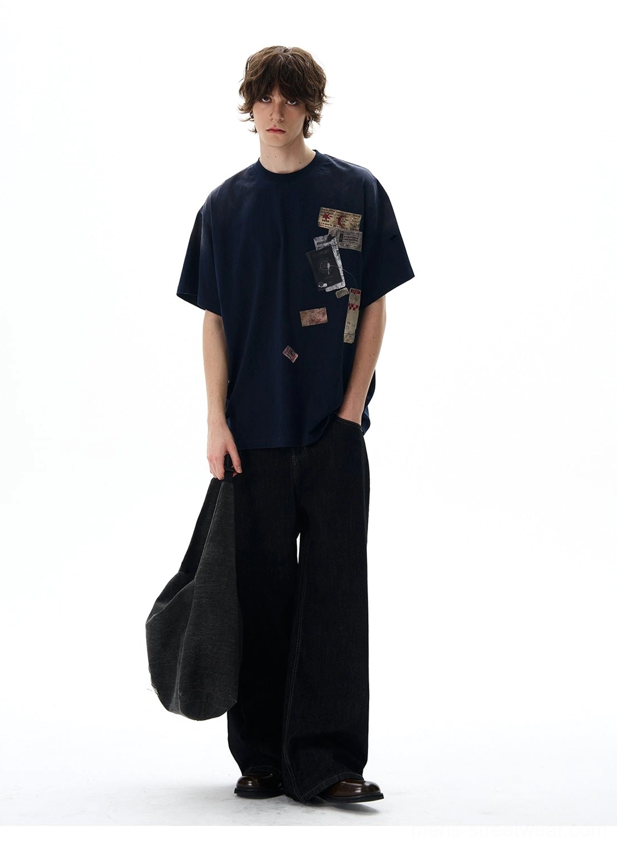 Navy oversized travel graphic T-shirt with vintage passport prints styled with black wide-leg jeans and canvas tote bag