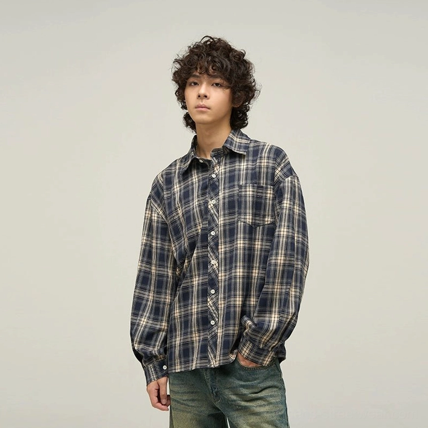 Male model wearing loose navy and warm beige tartan oversized button-up shirt with washed vintage denim jeans