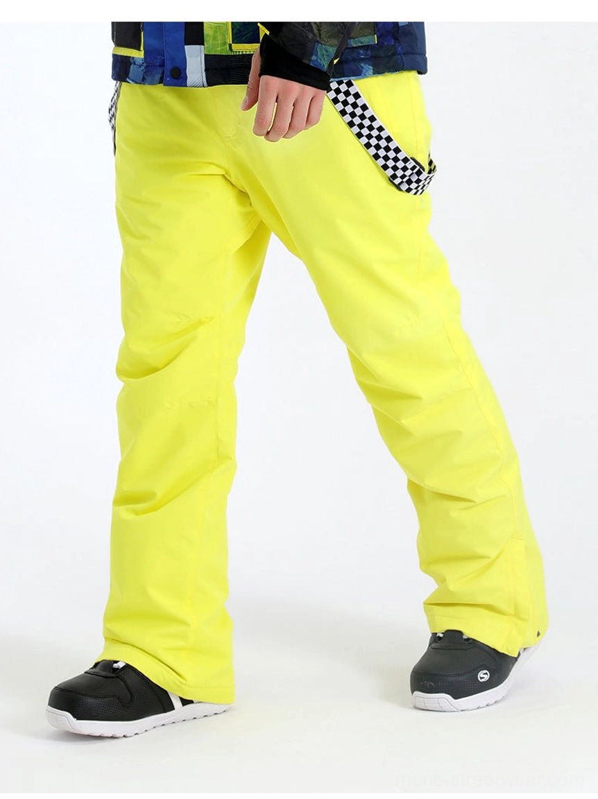 Neon yellow detachable checkerboard suspender snow pants shown from the side with a colorful printed ski jacket