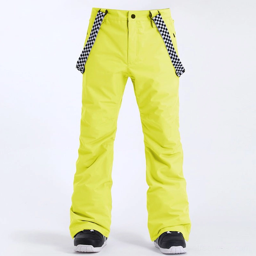Neon yellow detachable suspender snow pants with checkerboard straps styled over black ski shoes