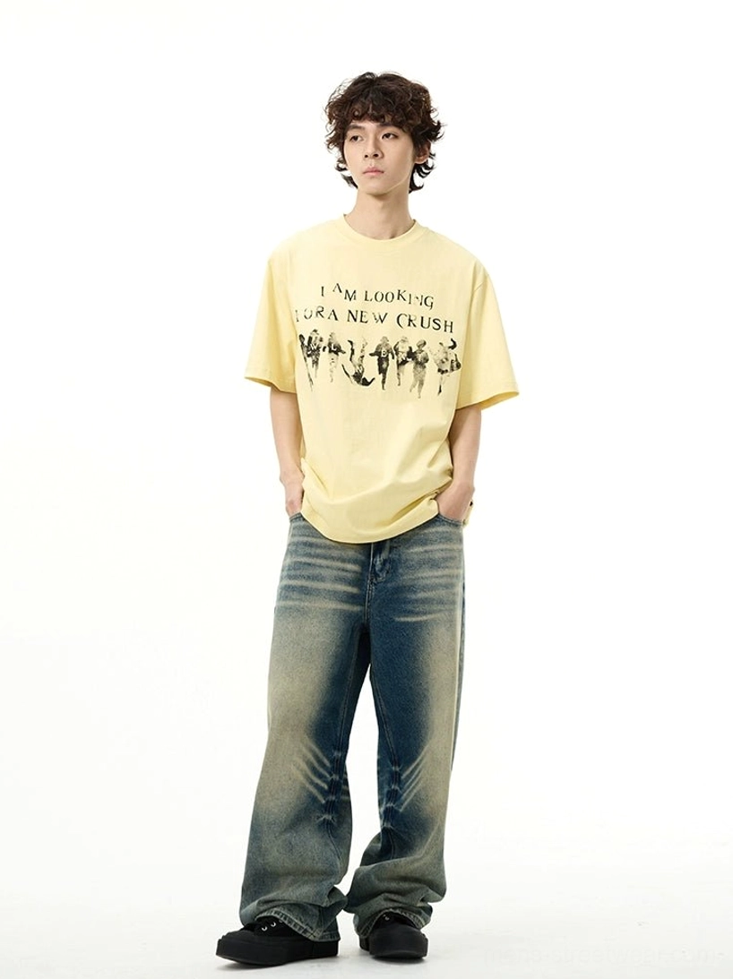 Male model wearing the yellow New Crush vintage graphic oversized streetwear t-shirt with baggy blue jeans and black shoes