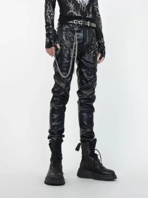 Front full-body view of black faux leather punk pants with silver rivets, decorative zippers, chain details, and a slim stacked techwear silhouette