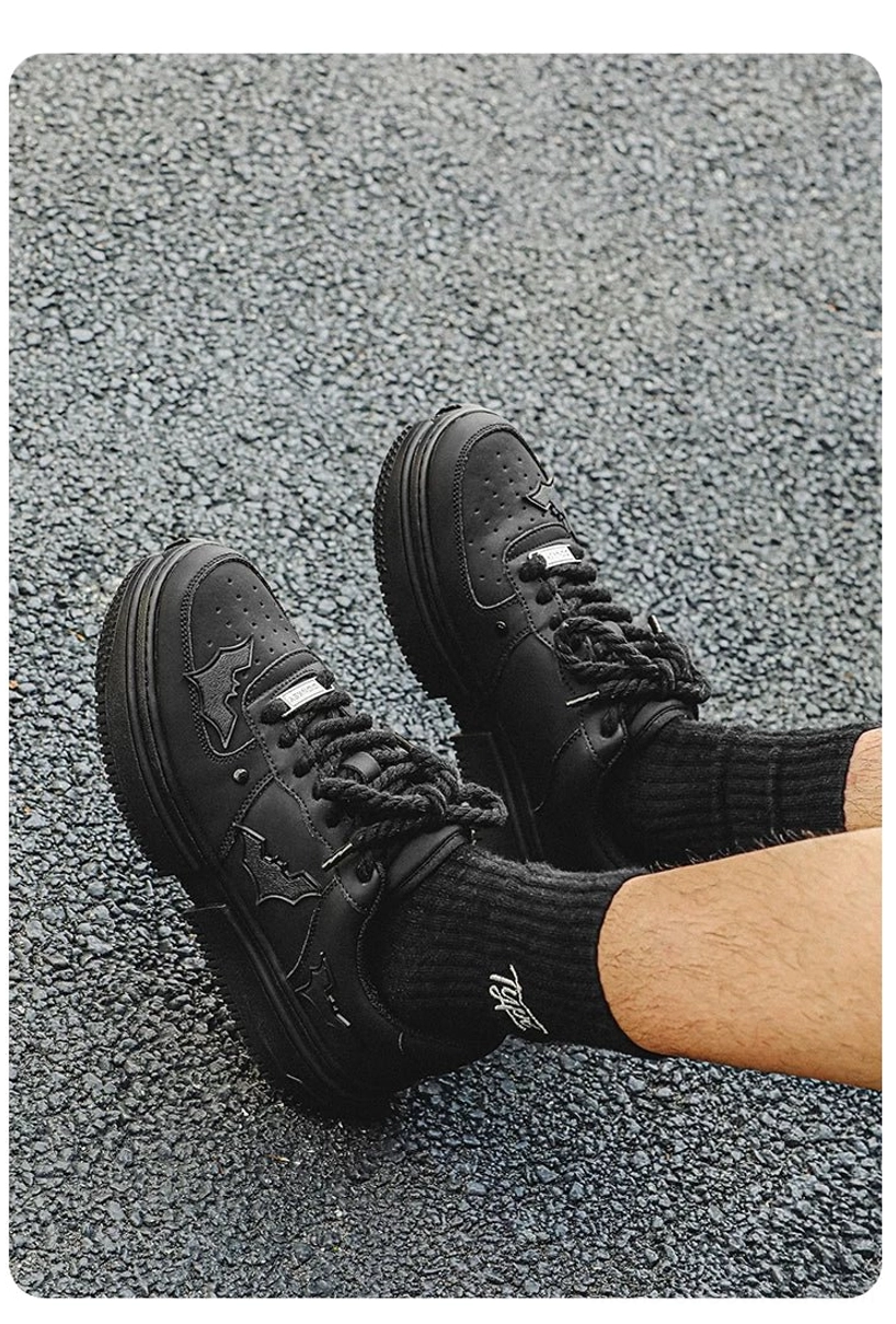 Close-up of black platform streetwear sneakers worn with crew socks showing chunky rope laces and metal tongue detail