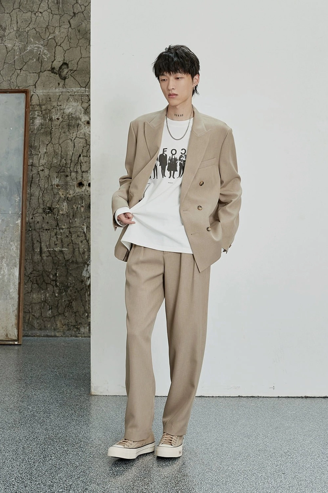 Oatmeal double-pleated dress pants styled with a beige blazer and graphic T-shirt