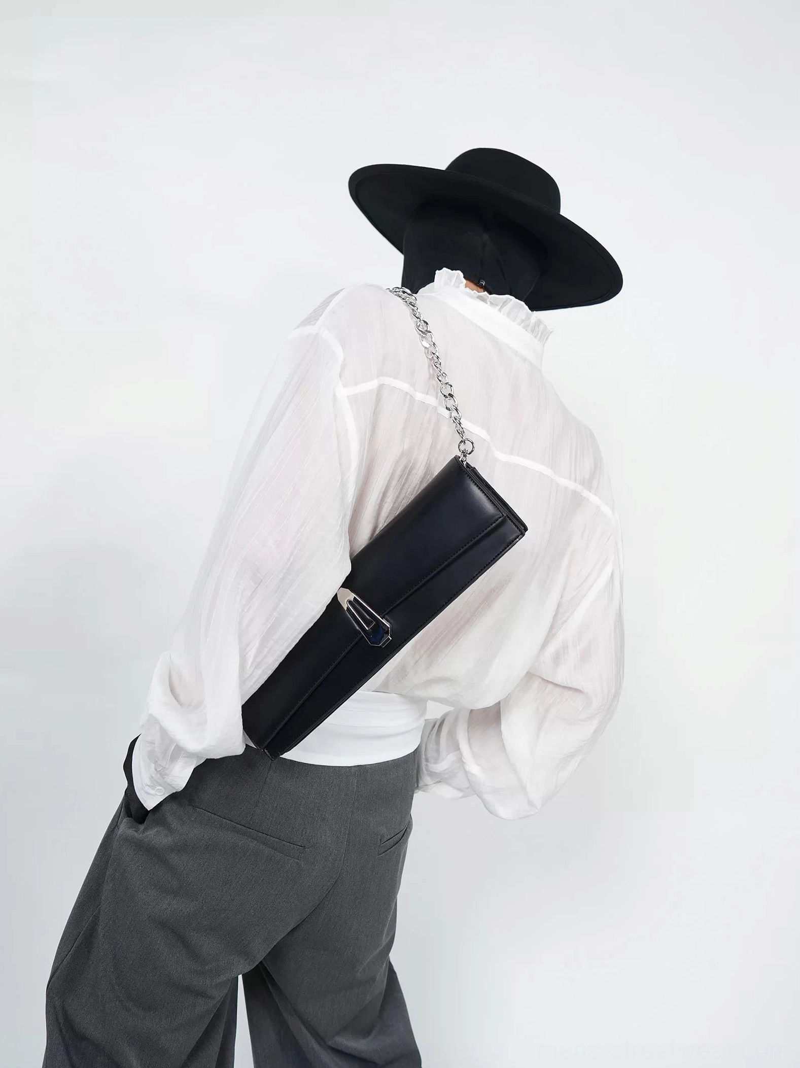 Back view of obsidian black chain shoulder clutch bag styled with white shirt and grey trousers for Seoul streetwear