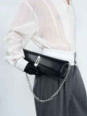 Obsidian black chain shoulder clutch bag close-up worn at the hip with silver curb chain and metal clasp