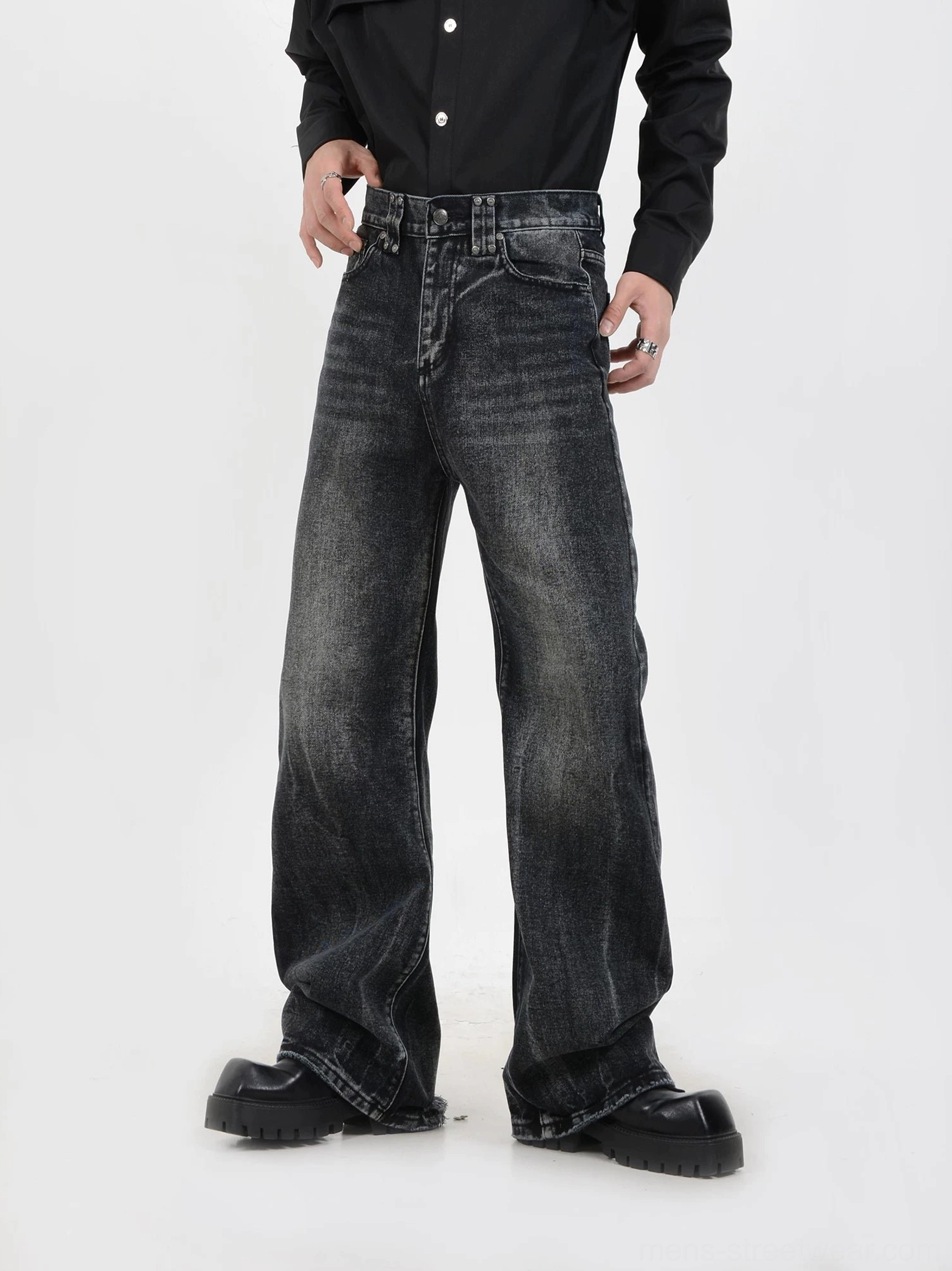Front three-quarter view of faded black wide-leg jeans showing button fly closure, vintage stone wash, relaxed Korean streetwear silhouette, and platform leather shoes