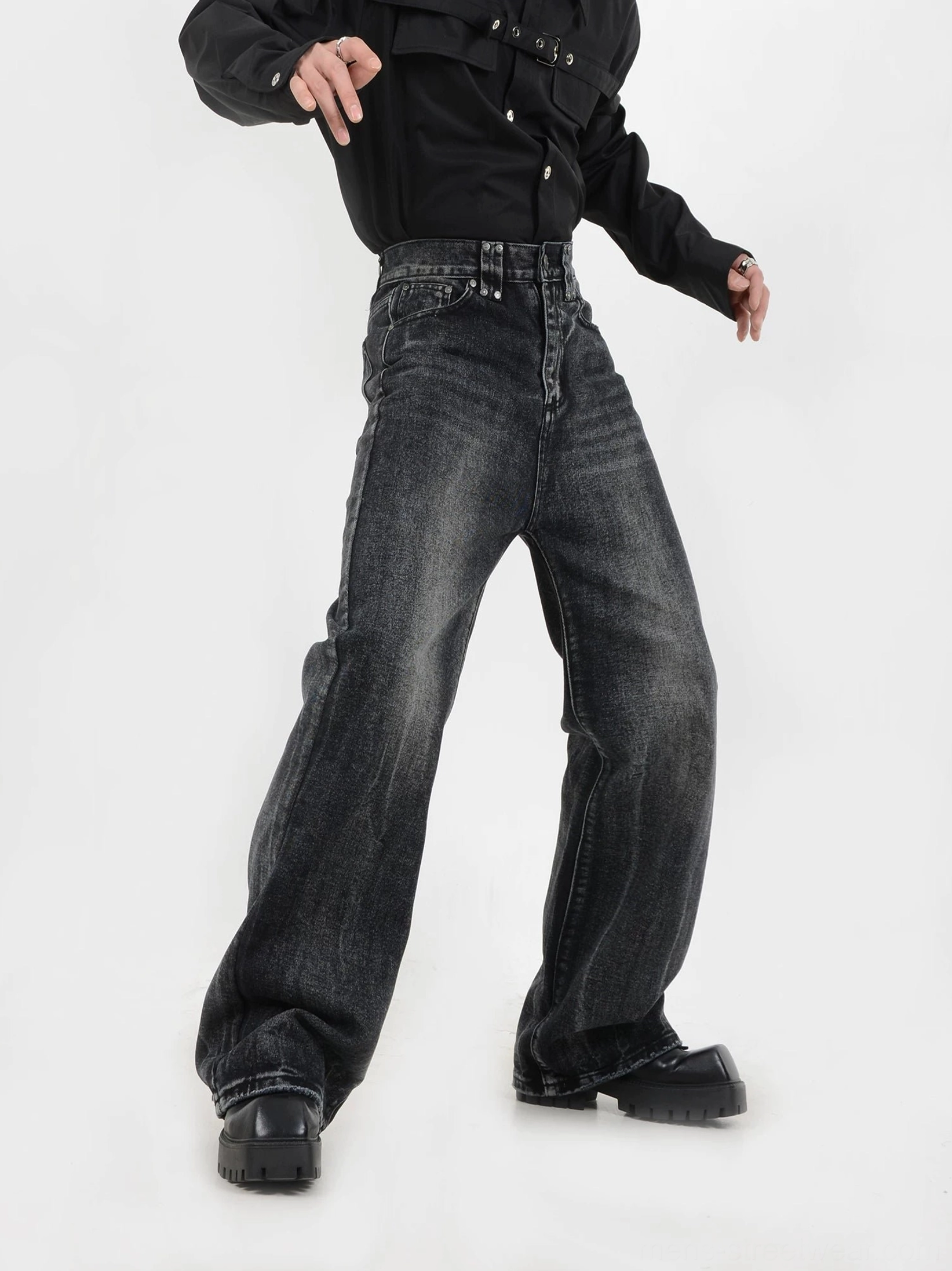 Side view of relaxed wide-leg vintage black jeans with acid wash fading, wide hem, classic denim hardware, and chunky work boots