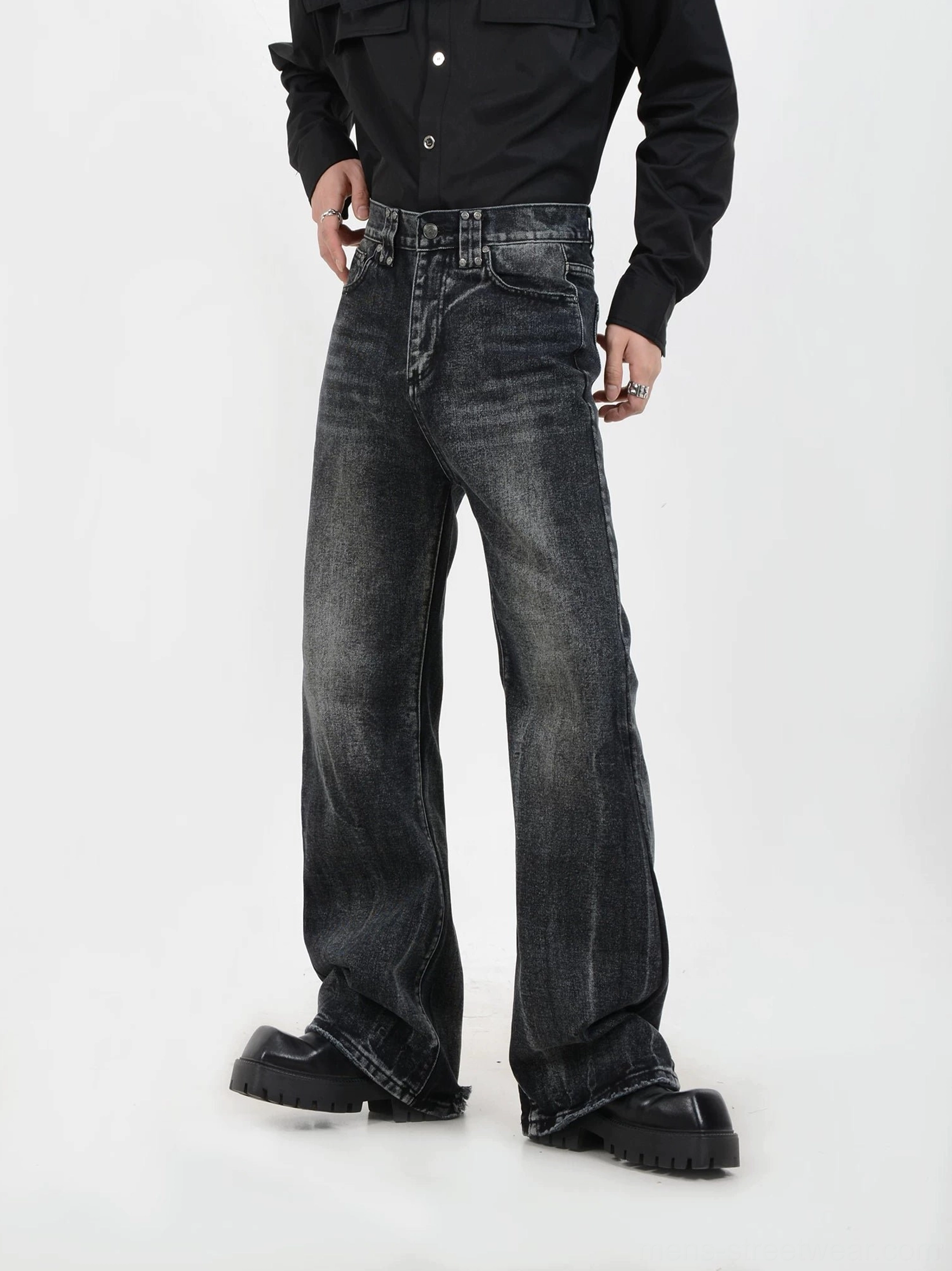Front side view of vintage washed black jeans with faded stone wash, roomy wide-leg cut, classic front pockets, and chunky leather footwear