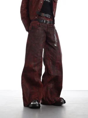 Crimson distressed ultra-wide leg denim pants shown from the front with a brown leather jacket and underground punk streetwear accessories