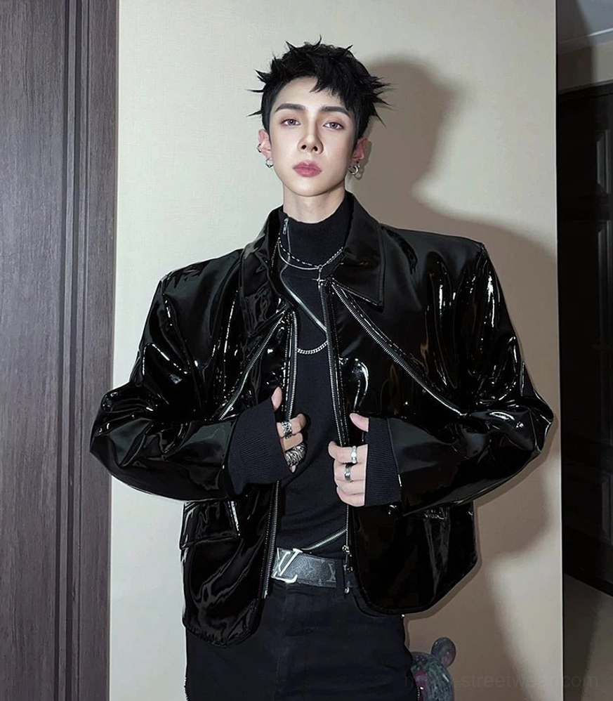 Black high-gloss cropped moto jacket with sculpted shoulders and front zipper worn in a dark streetwear outfit