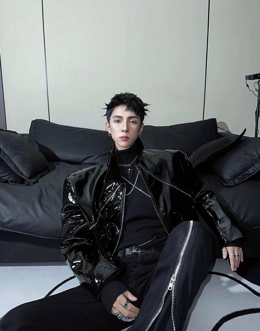 Black high-gloss cropped moto jacket styled with layered silver necklaces and zippered black streetwear pants
