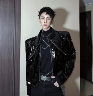 Three-quarter view of black glossy PU cropped moto jacket with structured shoulders and zipper closure