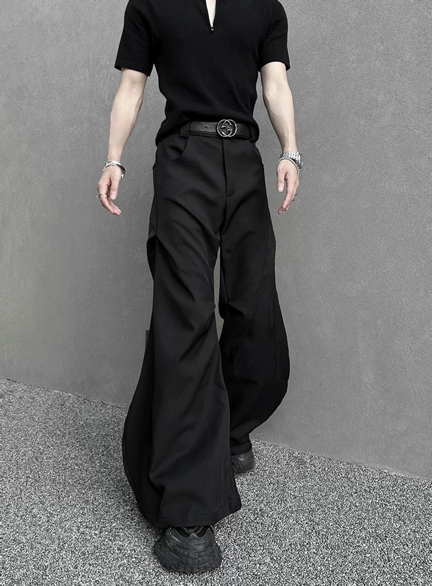 Front view of black high-waisted hyperwide flare cargo pants with a simple leather belt, dramatic wide hem, and minimalist dark streetwear styling