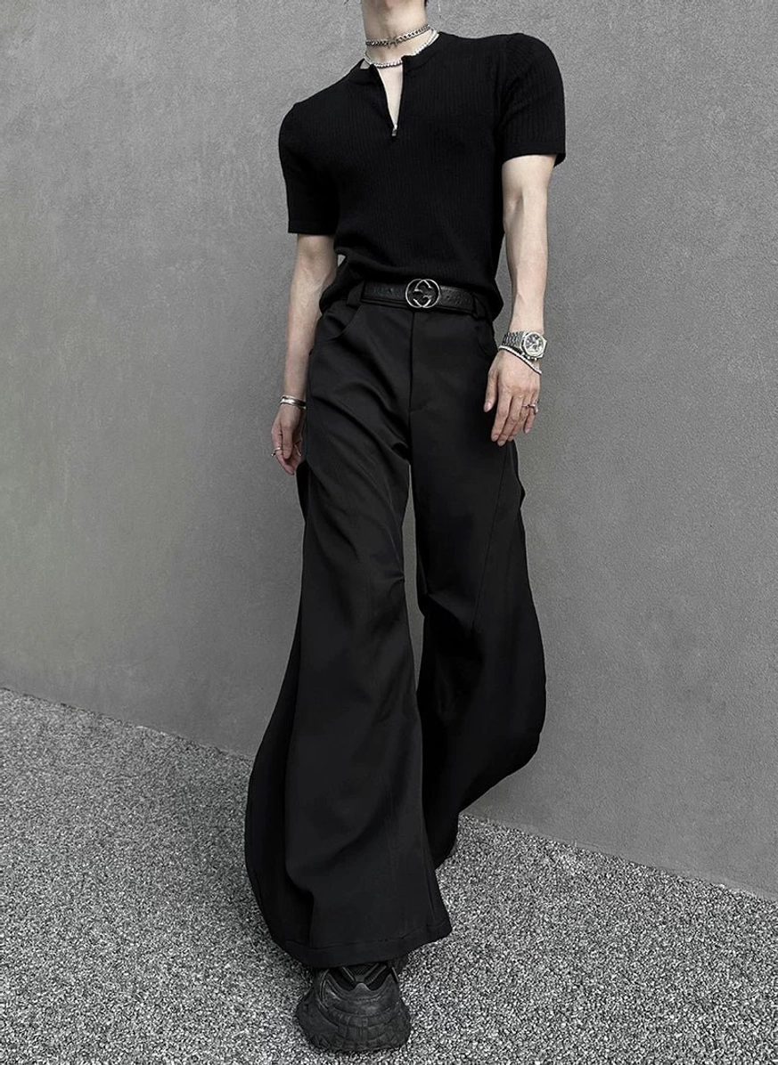 Three-quarter view of black ultra-flared cargo-style trousers with a floor-length hem, minimalist black henley top, and bold Korean streetwear silhouette